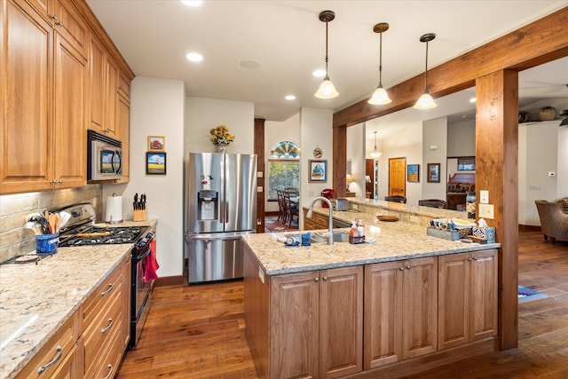 kitchen featuring light stone countertops, backsplash, stainless steel appliances, decorative light fixtures, and dark hardwood / wood-style floors