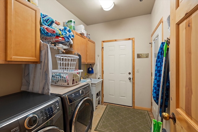 clothes washing area featuring separate washer and dryer, light tile patterned floors, and cabinets