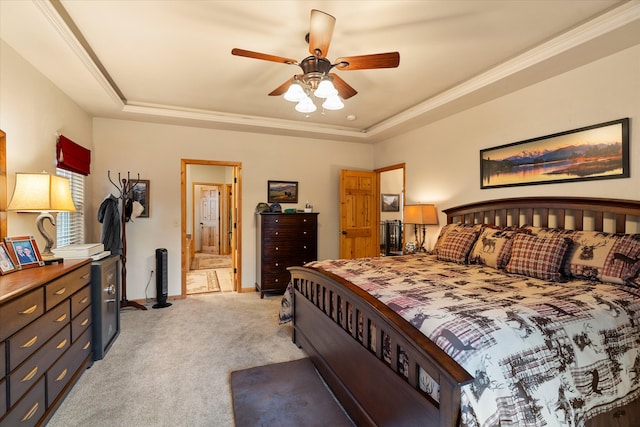 carpeted bedroom featuring a raised ceiling, ensuite bath, ceiling fan, and crown molding