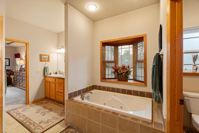 bathroom featuring vanity, a relaxing tiled tub, and toilet