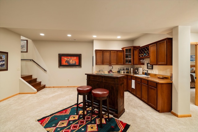 kitchen with a breakfast bar area, a center island, light colored carpet, and sink