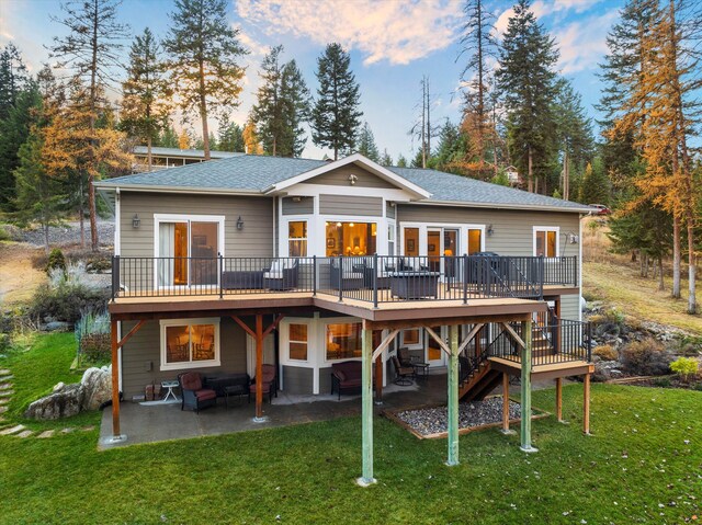 back house at dusk with an outdoor living space, a yard, a patio, and a wooden deck