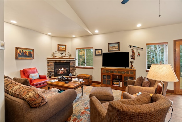 living room featuring a stone fireplace, plenty of natural light, vaulted ceiling, and hardwood / wood-style flooring