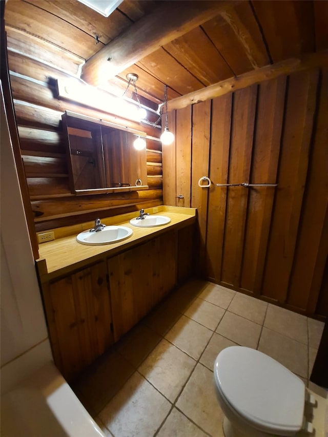 bathroom featuring rustic walls, vanity, wooden ceiling, tile patterned flooring, and toilet