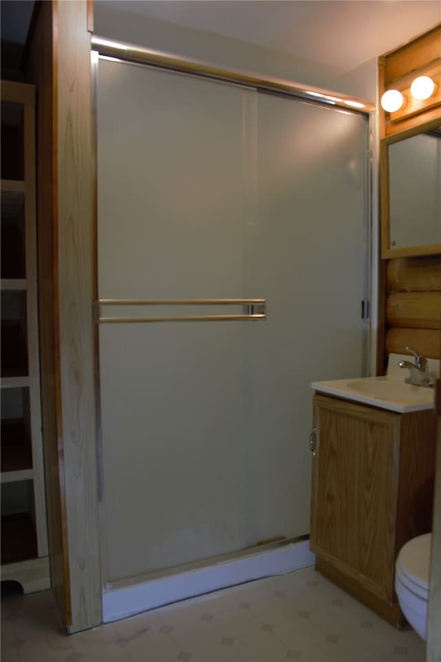 bathroom with vanity, toilet, and a shower with door