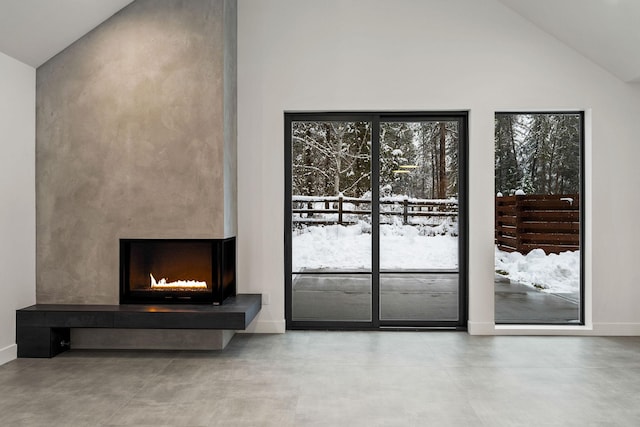 1027 State Park Rd, Whitefish, MT 59937 - unfurnished living room with finished concrete flooring, a warm lit fireplace, and high vaulted ceiling