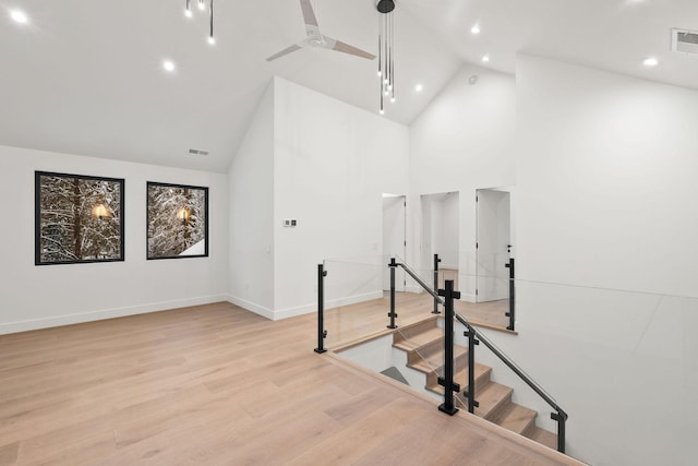 stairway featuring ceiling fan, high vaulted ceiling, and hardwood / wood-style flooring