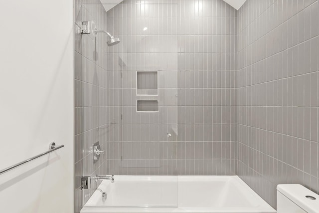 bathroom featuring toilet and tiled shower / bath