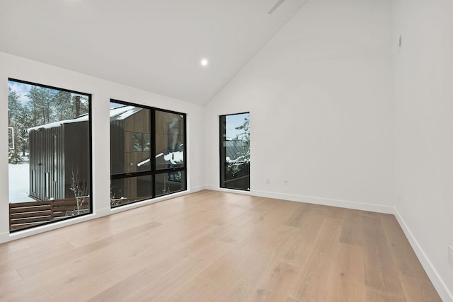 unfurnished room featuring light wood-type flooring and high vaulted ceiling