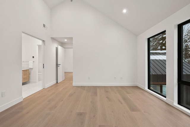 empty room with light hardwood / wood-style floors and high vaulted ceiling