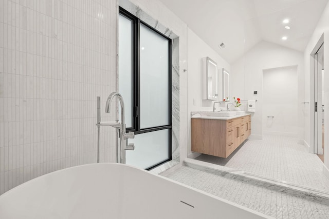 bathroom with vanity, lofted ceiling, and a bath