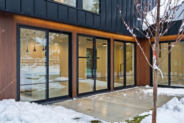 snow covered property entrance featuring a patio