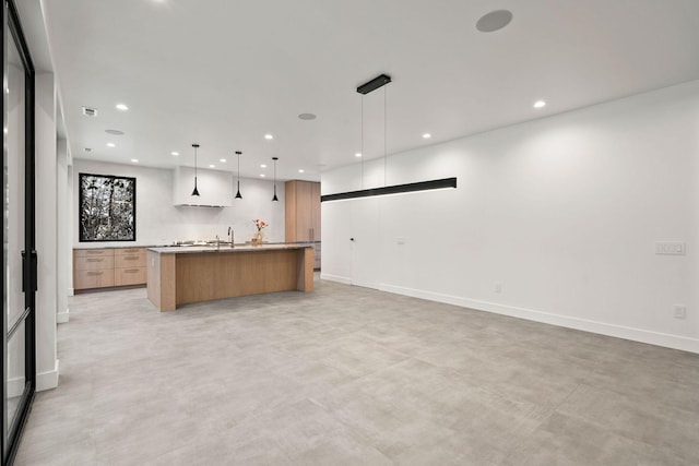 kitchen with a kitchen island with sink, sink, and pendant lighting