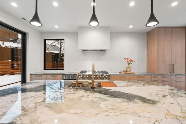 interior space with pendant lighting, stainless steel stove, light stone countertops, and extractor fan