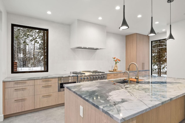 kitchen with light stone countertops, wall chimney exhaust hood, stainless steel appliances, decorative light fixtures, and light brown cabinetry