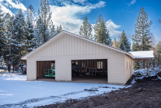 snow covered property with an outdoor structure and a garage