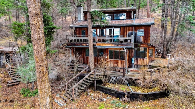 rear view of house featuring stairway, a chimney, and a deck