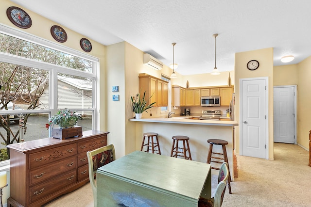 kitchen featuring pendant lighting, a wall mounted air conditioner, light carpet, appliances with stainless steel finishes, and kitchen peninsula