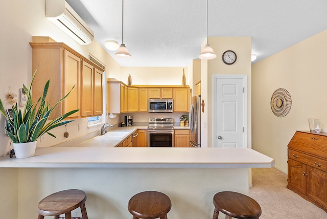 kitchen with sink, kitchen peninsula, decorative light fixtures, a kitchen bar, and appliances with stainless steel finishes