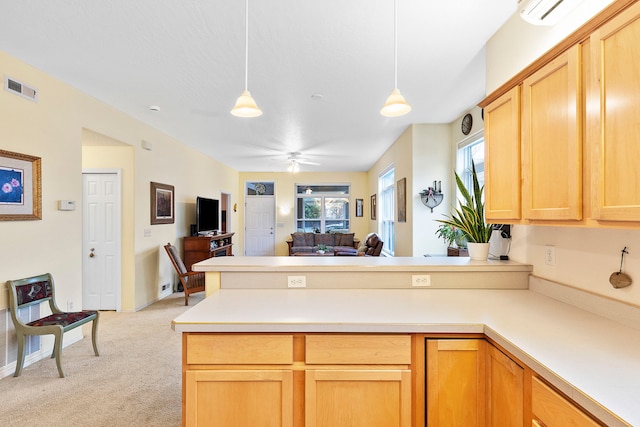 kitchen featuring pendant lighting, light carpet, ceiling fan, light brown cabinetry, and kitchen peninsula