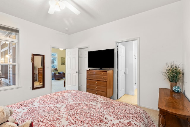 bedroom with ensuite bathroom, ceiling fan, light colored carpet, and multiple windows