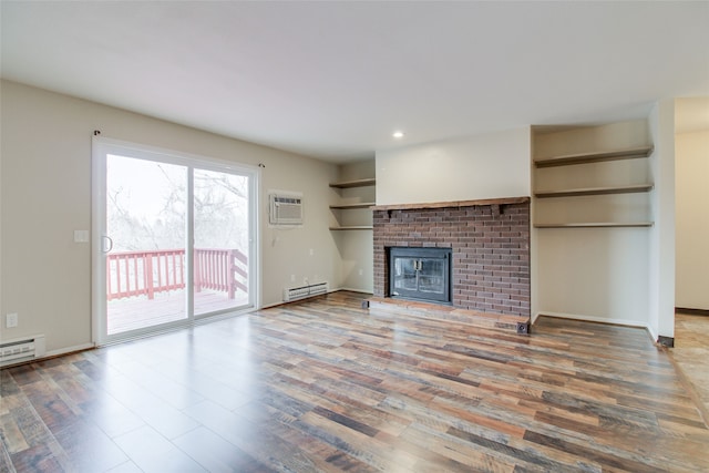 unfurnished living room with a wall mounted air conditioner, hardwood / wood-style floors, a brick fireplace, and baseboard heating