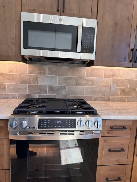 7026 Max Dr, Missoula, MT 59803 - kitchen with stainless steel appliances, backsplash, and light stone counters