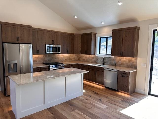 7026 Max Dr, Missoula, MT 59803 - kitchen with stainless steel appliances, a center island, light wood-style floors, vaulted ceiling, and tasteful backsplash