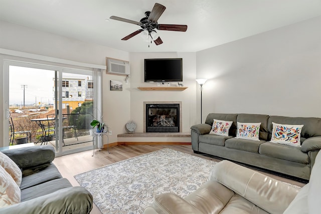 living room with ceiling fan, light hardwood / wood-style floors, and a wall mounted air conditioner