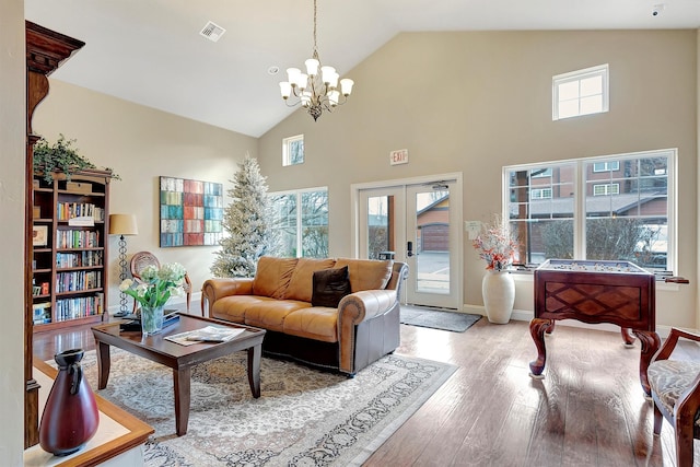 living room with french doors, light hardwood / wood-style floors, high vaulted ceiling, and a wealth of natural light