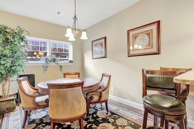 dining area with wood-type flooring and a chandelier