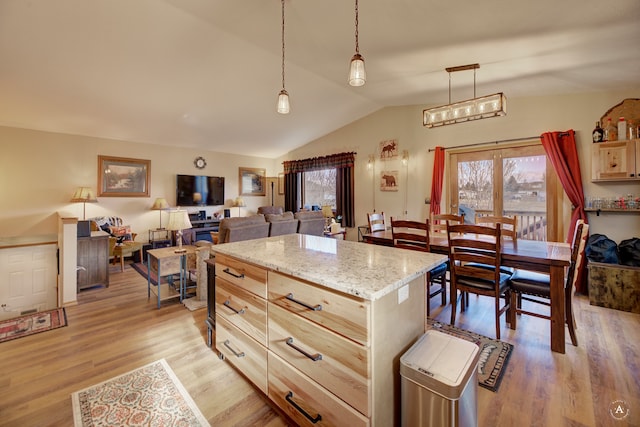 kitchen with light stone countertops, light hardwood / wood-style flooring, decorative light fixtures, vaulted ceiling, and a kitchen island