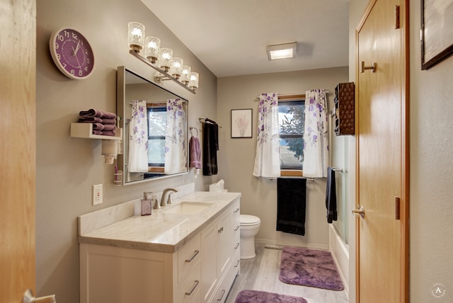 full bathroom featuring combined bath / shower with glass door, vanity, hardwood / wood-style flooring, and toilet