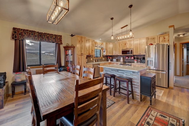 dining area with light hardwood / wood-style flooring, lofted ceiling, and sink