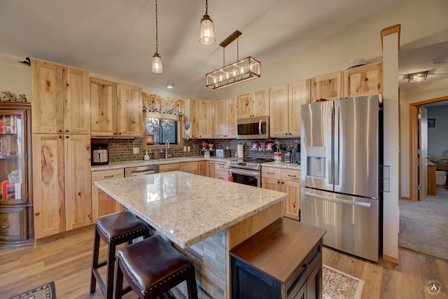 kitchen featuring pendant lighting, a center island, light brown cabinets, and appliances with stainless steel finishes