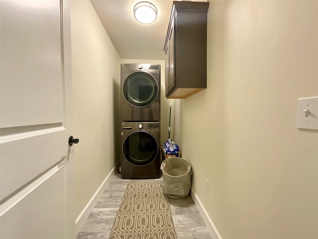 washroom featuring stacked washer and dryer and cabinets