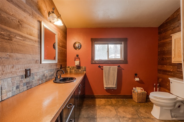 bathroom with tasteful backsplash, tile patterned floors, wood walls, toilet, and vanity