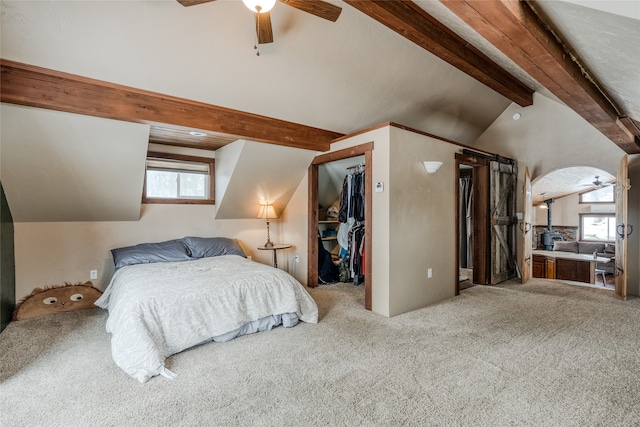 carpeted bedroom with ceiling fan, lofted ceiling with beams, a spacious closet, and a closet