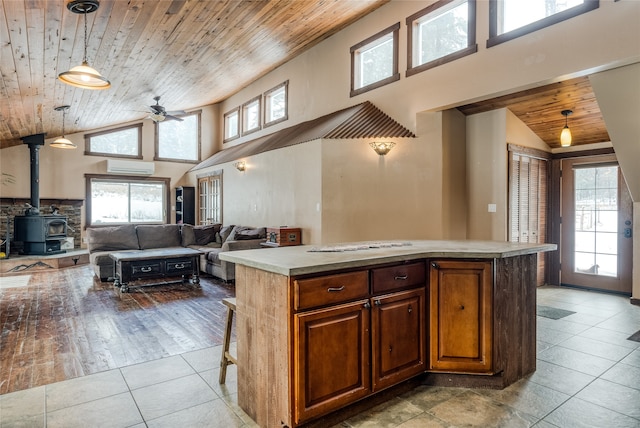 kitchen with pendant lighting, a kitchen island, a wealth of natural light, and a wood stove