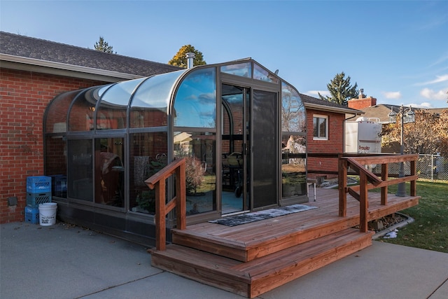 rear view of property featuring a sunroom and a wooden deck