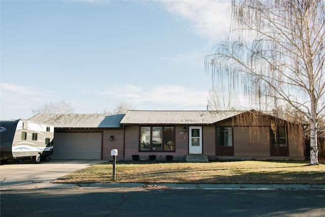 ranch-style home with a front lawn, entry steps, concrete driveway, roof with shingles, and an attached garage