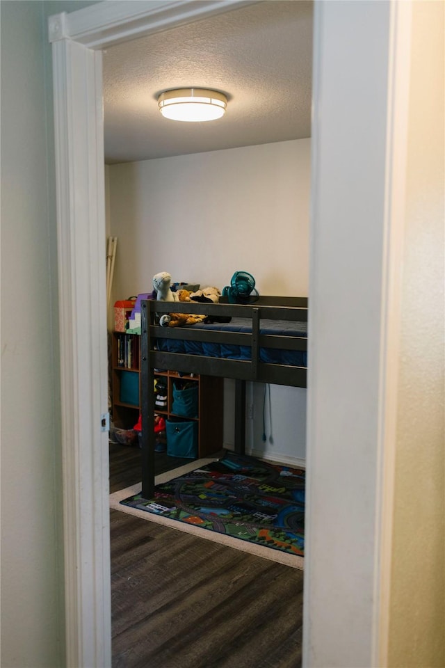 bedroom with a textured ceiling and wood finished floors