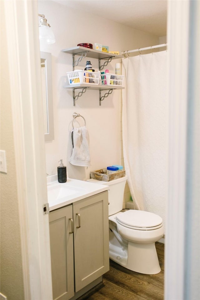 full bathroom with a shower with shower curtain, toilet, wood finished floors, and vanity