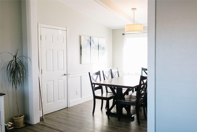 dining space with lofted ceiling, dark wood-style floors, wainscoting, and a decorative wall