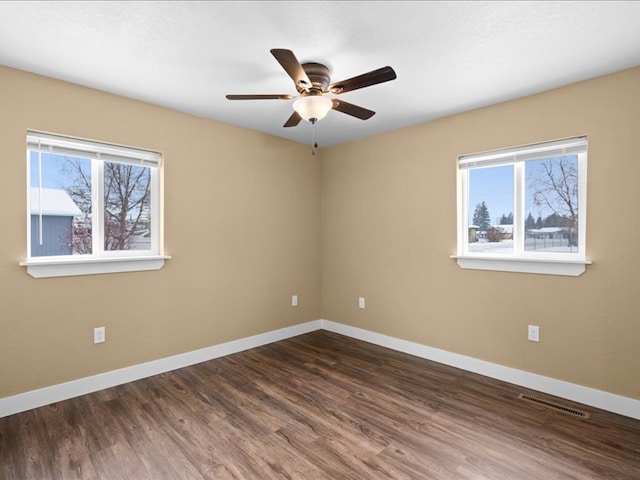 empty room with dark wood-type flooring, ceiling fan, and a healthy amount of sunlight