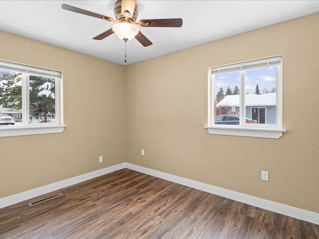 spare room featuring ceiling fan, a healthy amount of sunlight, and dark hardwood / wood-style flooring