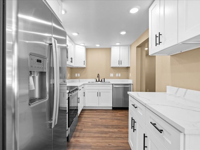 kitchen with light stone countertops, sink, dark hardwood / wood-style floors, white cabinets, and appliances with stainless steel finishes