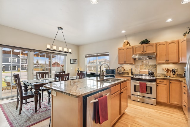 kitchen with a center island with sink, sink, light hardwood / wood-style flooring, light stone countertops, and appliances with stainless steel finishes