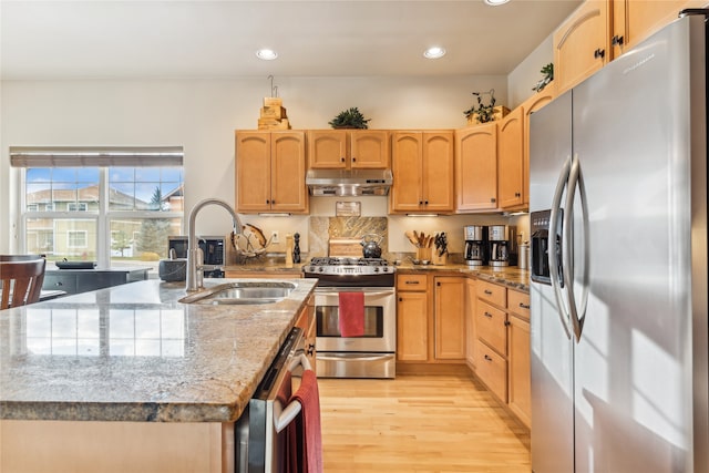 kitchen featuring light brown cabinets, sink, light stone countertops, appliances with stainless steel finishes, and light hardwood / wood-style floors