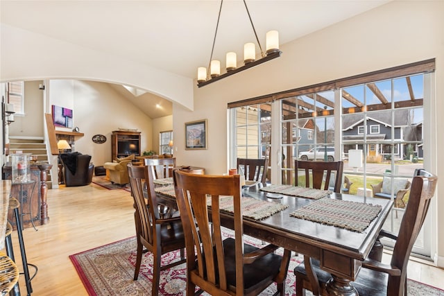 659 Copperwood Ct, Whitefish, MT 59937 - dining room featuring arched walkways, light wood-type flooring, vaulted ceiling, and a fireplace